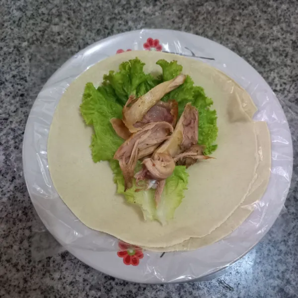 Tata daun selada di atas kulit kebab, lalu tambahkan suwiran daging ayam goreng.