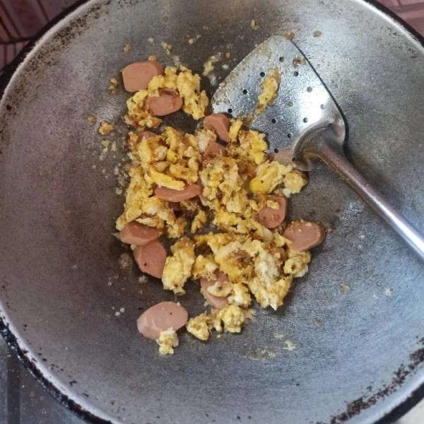 Setelah bumbu matang masukkan telur goreng orak-arik, kemudian masukkan sosis, aduk sebentar.