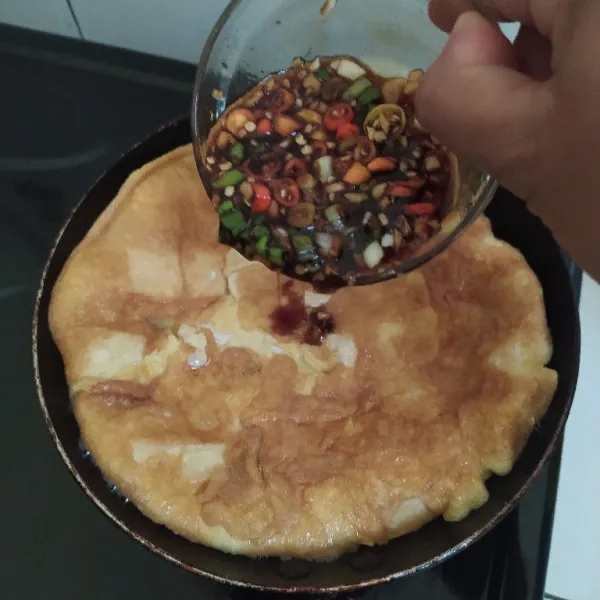 Balik telur lalu siram dengan kecap dan bumbu tadi, ratakan lalu balik lagi sekali dan ratakan kembali. Angkat, sajikan.