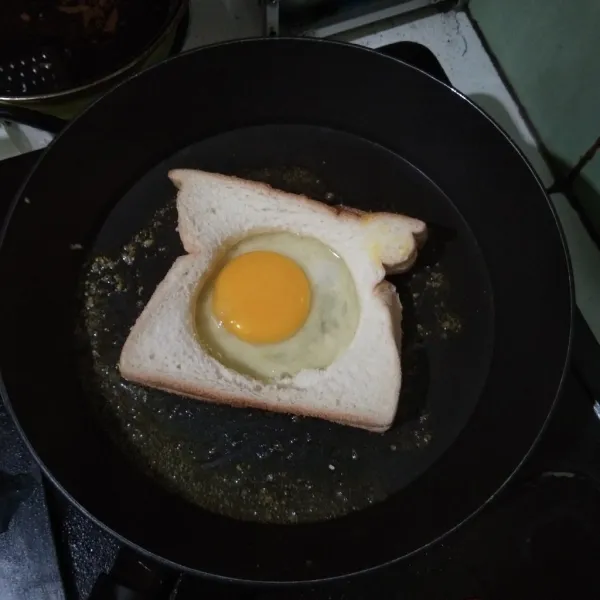 Tambahkan telur yang sudah dipecahkan ke dalam lubang roti.