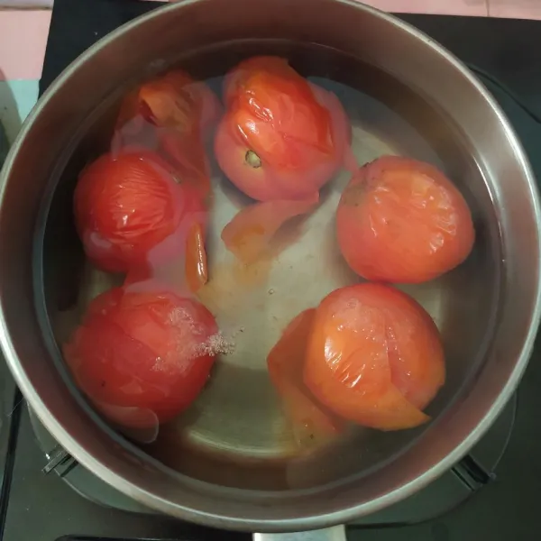Buat guratan menyilang di ujung tomat supaya nanti mudah mengupas kulit arinya. Rebus tomat hingga matang.