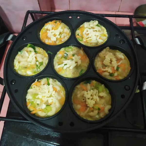 Panaskan cetakan dengan api kecil. Lalu olesi dengan minyak.
Tuang adonan makaroni.
Setelah hampir matang, beri parutan keju quick melt.