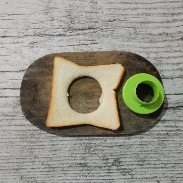 Ambil satu lembar roti, lalu lubangi tengahnya dengan menggunakan ring cutter. Sisihkan.