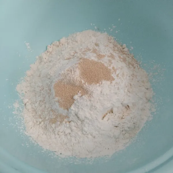 Campurkan tepung terigu, tepung ketan dan ragi jadi satu dalam wadah.