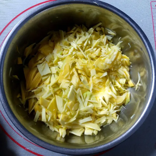 Kupas dan cacah mangga muda. Tempatkan hasilnya wadah yang cukup besar.