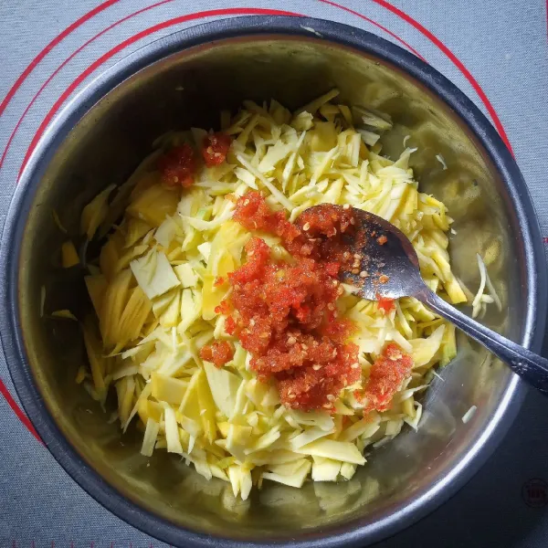 Pindahkan ke wadah mangga muda, tambahkan sisa gula pasir, aduk sampai tercampur rata.