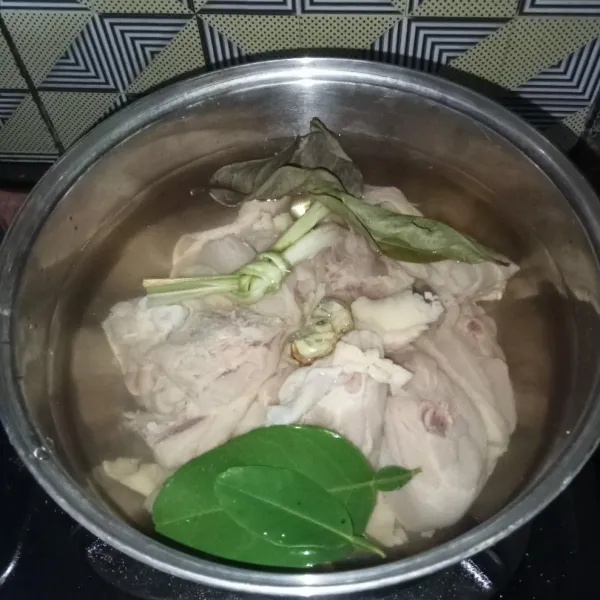 Rebus ayam, bumbu aromatik dan air di panci.
