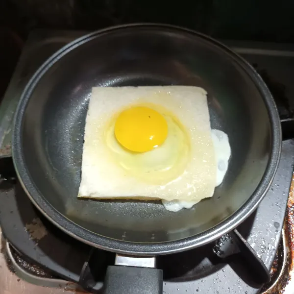 Lalu lelehkan margarin di atas teflon. Kemudian masukkan roti dan ceplokan telur di atas lubang roti.