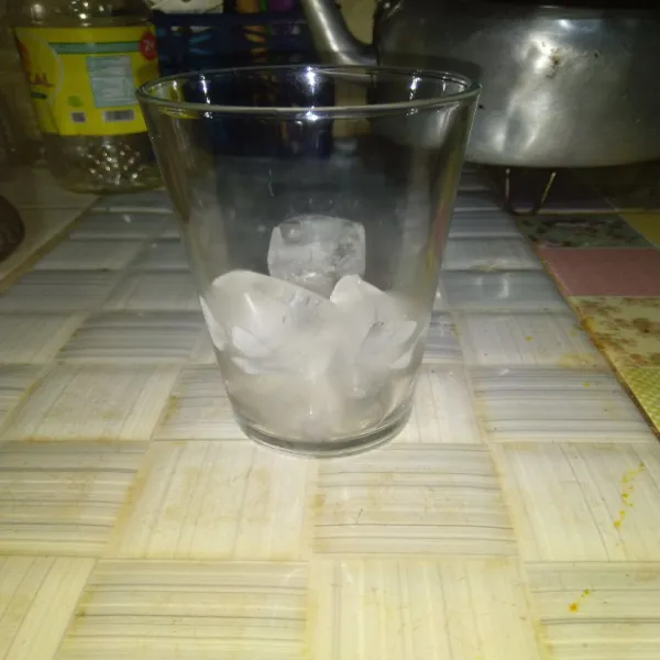 Siapkan gelas, lalu tuang secukupnya es batu kedalamnya.