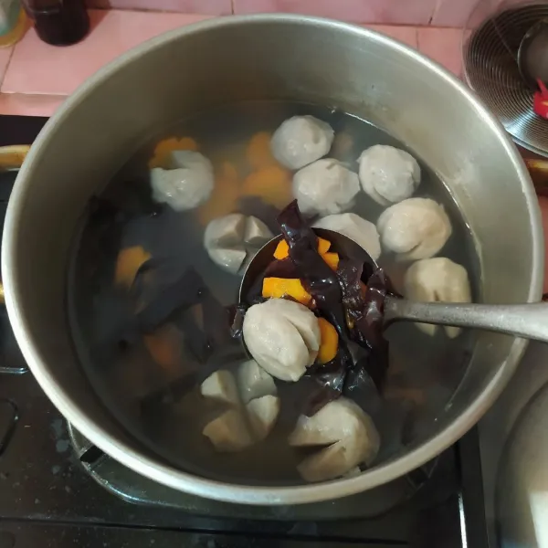 Rebus air hingga mendidih, lalu masukkan bakso, wortel dan jamur kuping.