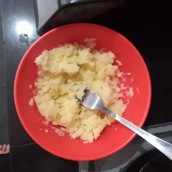 Rebus kentang hingga matang dan empuk lalu angkat dan selagi panas, haluskan dengan bantuan garpu, sisihkan.