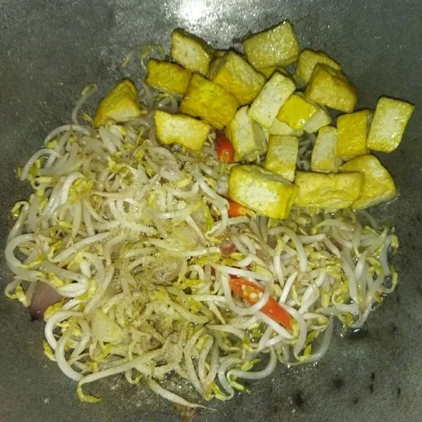 Tambahkan tahu kuning, garam, kaldu bubuk, lada bubuk dan gula pasir, aduk rata, masak hingga toge layu.