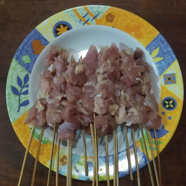 Susun potongan daging ayam di tusukan sate.