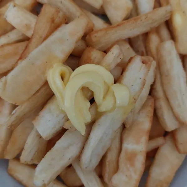 Bubuhi singkong goreng yang masih panas dengan margarine, aduk.