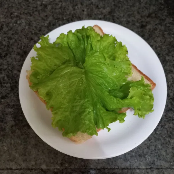 Siapkan roti yang telah dikukus, tata daun selada di atasnya