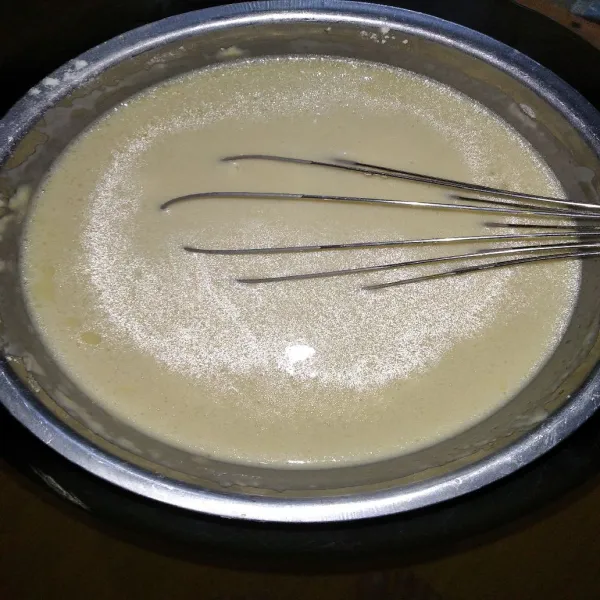 Tuang air sedikit demi sedikit ke dalam adonan tepung yang sudah tercampur telur, aduk hingga rata dan tidak bergerindil.