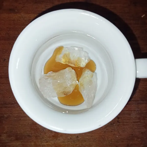 Dalam gelas saji masukkan gula batu dan madu.