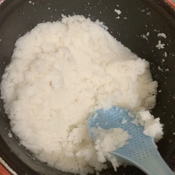 Setelah magic com selesai memasak dan nasi matang, aduk serta tekan-tekan nasi hingga teksturnya halus menjadi lontong. Berikan garam lalu aduk kembali.