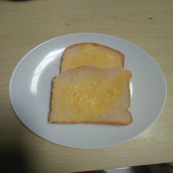 Oles roti tawar yang utuh dengan margarin.