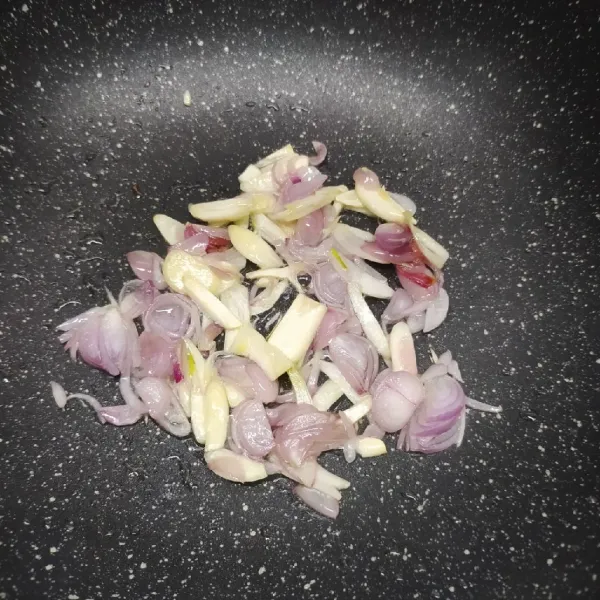 Tumis irisan bawang merah dan bawang putih sampai layu dan harum.