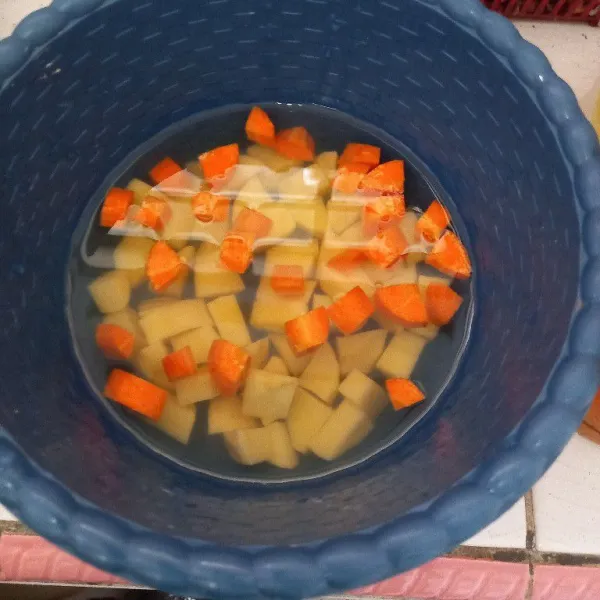 Kupas kulit kentang dan wortel, cuci bersih dan potong bentuk kotak.