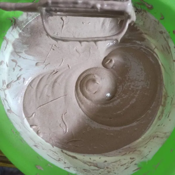 Turunkan kembali kecepatan mixer ke speed rendah masukkan tepung dan coklat bubuk sambil diayak mix sebentar asal rata.