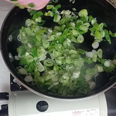 Panaskan minyak goreng, Tumis daun bawang dan bawang putih hingga harum.