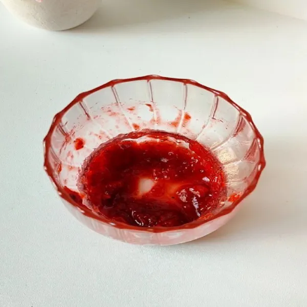 Siapkan gelas, tuang selai strawberry. Oleskan ke bagian tepi gelas agar menarik.