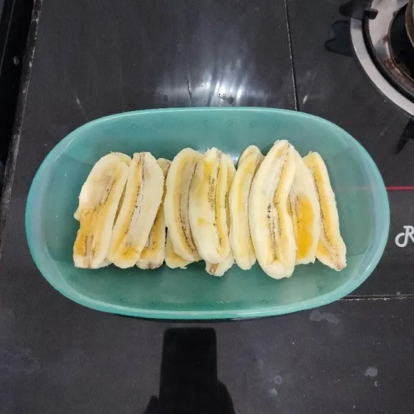 Kupas pisang, lalu belah memanjang menjadi 2 bagian.