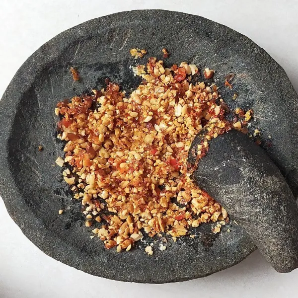 Haluskan bawang putih yang sudah di goreng tadi, bersama kacang tanah,cabai rawit merah tumbuk kasar