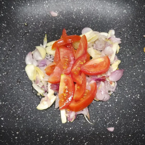 Tumis bawang merah, bawang putih sampai layu dan harum. Masukkan irisan tomat, masak sambil tomat ditekan-tekan agar keluar airnya. Sisihkan ke tepi wajan.