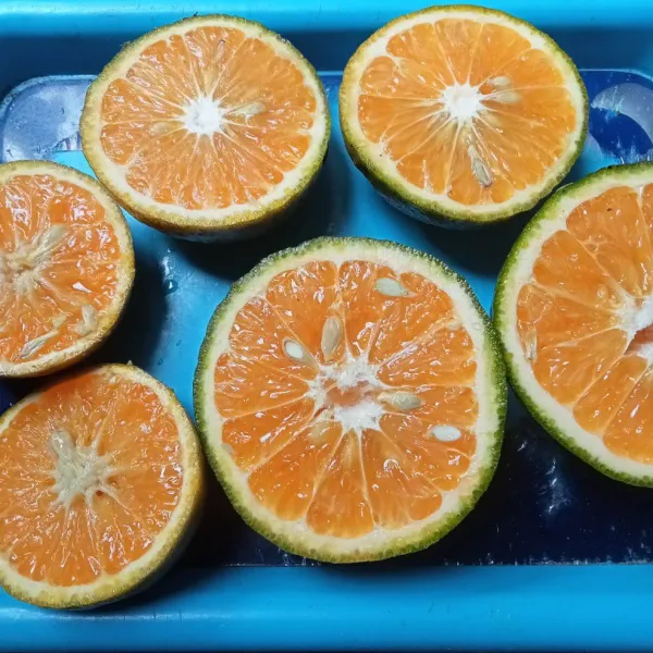Cuci buah jeruk dan belah dua.