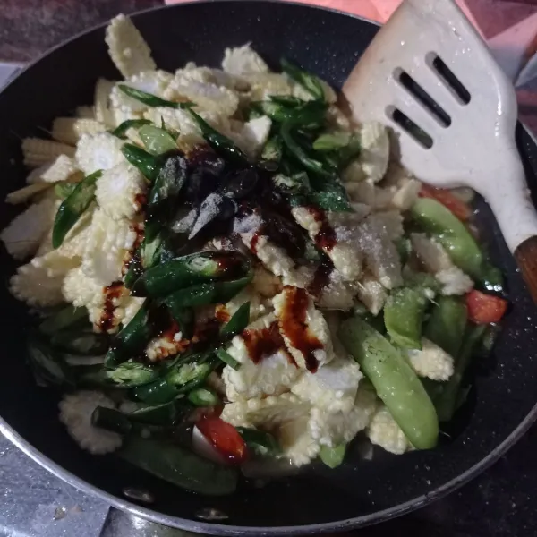 Masukkan irisan jagung muda, kapri, kecap manis, saus tiram, garam, gula, lada bubuk dan kaldu bubuk, aduk sampai tercampur rata.