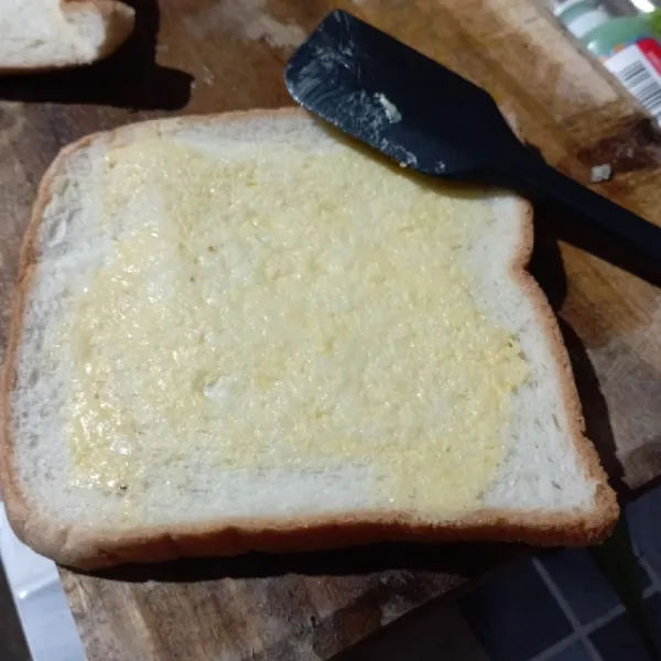 Olesi roti tawar dengan margarin di kedua sisi.