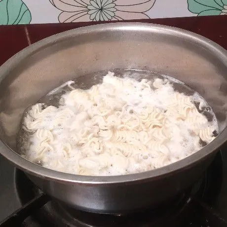 Siapkan mie kering. Rebus mie bersama kaldu bubuk, sampai setengah matang.