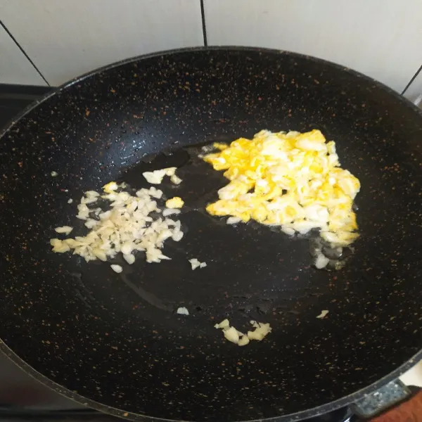 Panaskan minyak, Orak arik telur lalu sisihkan. Tumis bawang putih cincang hingga harum.