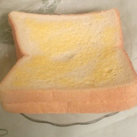 Tutup dengan roti tawar satunya. Kemudian oles bagian luar dengan margarine juga.