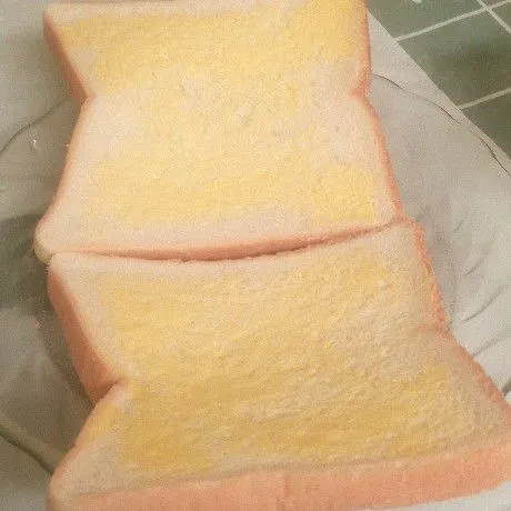 Oles bagian dalam roti tawar dengan margarine sampai rata.