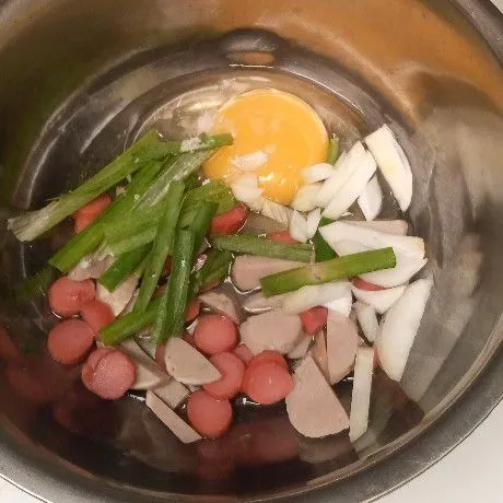 Ceplok telor di mangkuk, tambahkan sosis, bakso, irisan daun bawang, dan bawang bombay.