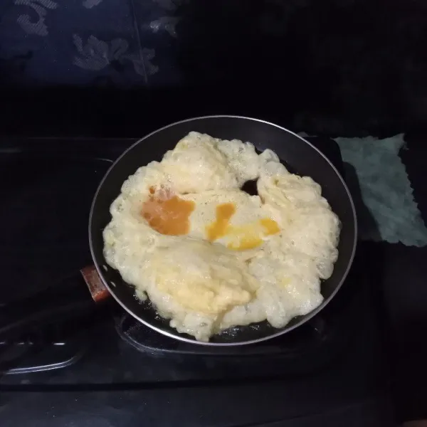 Masukkan telur, agak tinggi jaraknya dari minyak saat memasukkannya, agar telur mengeriting.