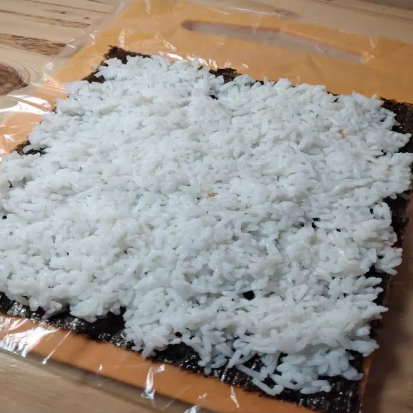 Siapkan nori, tata nasi putih di atasnya dengan rapi
