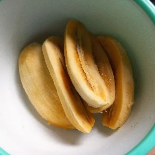 Kupas pisang kemudian belah menjadi 2 bagian.