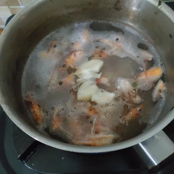 Tambahkan 2 siung bawang putih yang sudah di geprek. Lalu masak hingga mendidih dan kaldu harum.