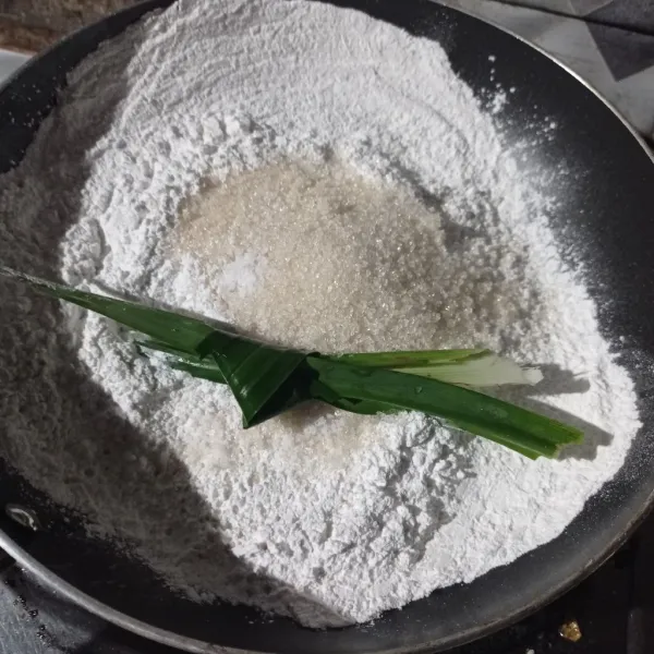 Masukan tepung beras, gula pasir, vanili bubuk, garam dan daun pandan ke dalam teflon.