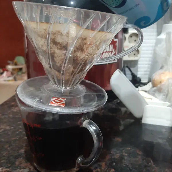 Tuang kopi melalui driper ke dalam wadah gelas ukur tunggu hingga selesai menetes