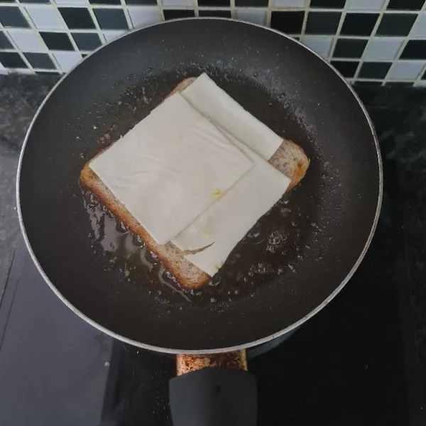 Masukkan satu lembar roti tawar. Tambahkan keju diatasnya.