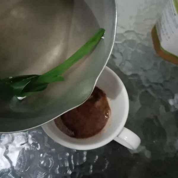 Lalu tuang air mendidih rebusan pandan ke dalam gelas kopi.