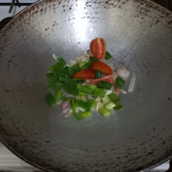 Masukkan irisan tomat dan daun bawang, aduk rata.