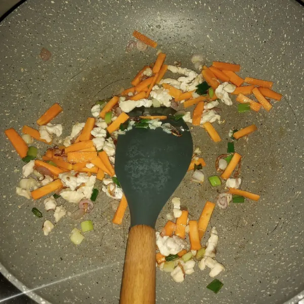 Panaskan minyak goreng, tumis bawang merah sampai layu. Masukkan ayam cincang, bawang putih dan setengan bagian daun bawang. Madak sampai ayam berhbah warna. Masukkan wortel, tumis sebentar.