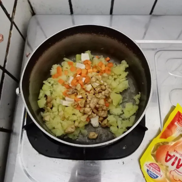 Lumatkan dengan garpu kentang yang telah dikukus. Masukkan wortel, tahu dan tumisan ayam. Aduk rata.